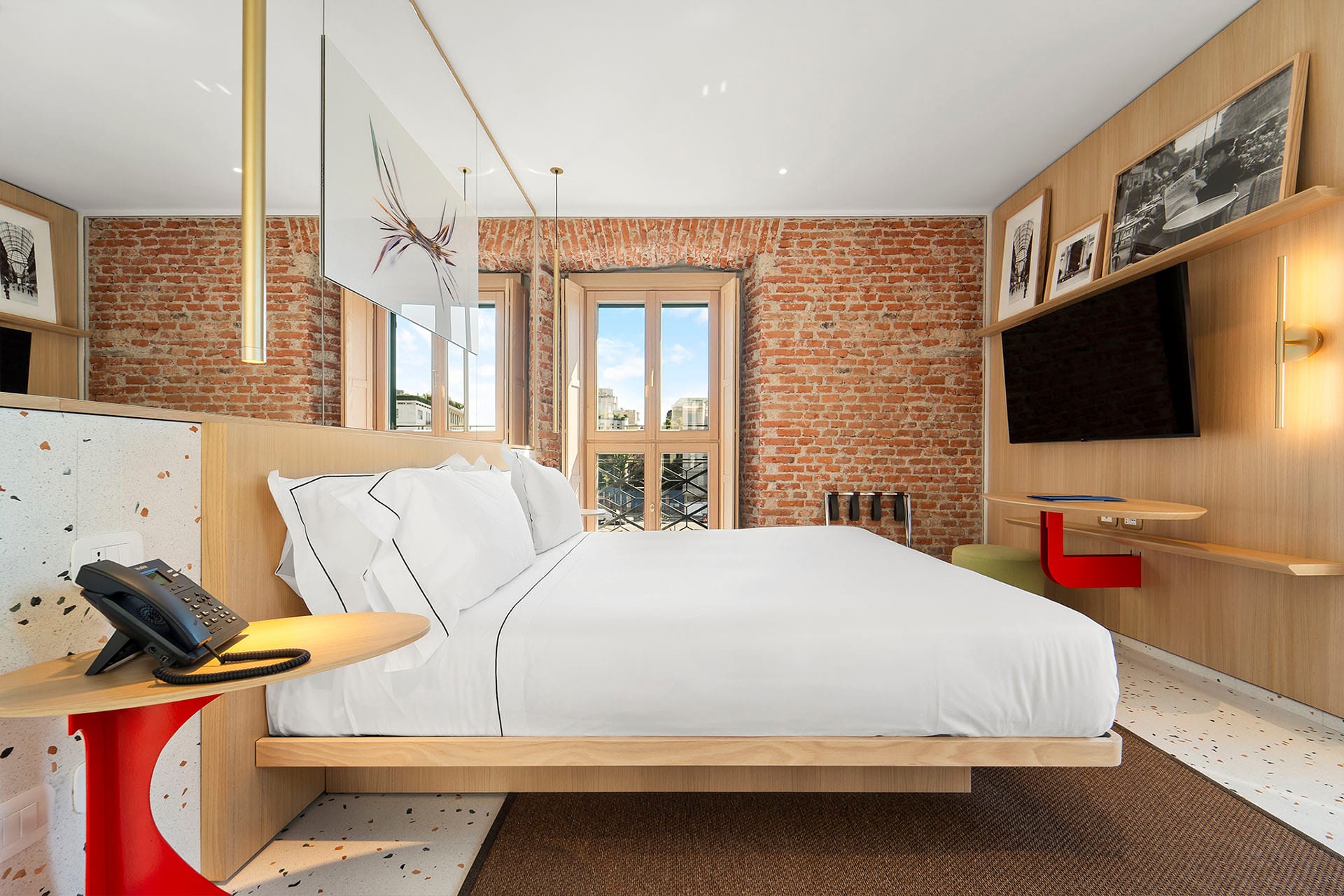 Detalle de Habitación Doble Comfort con cama de matrimonio y TV de pantalla plana en la pared del Hotel Milu en Milán