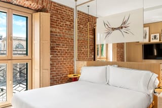 Dettaglio camera Superior Matrimoniale con letto matrimoniale e parete a mattoni Hotel Milu Milano